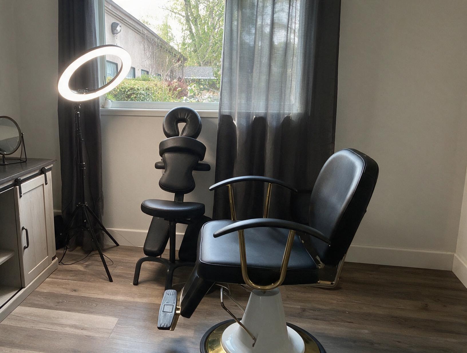 Empty treatment room with a black salon chair, a massage-style face-down chair